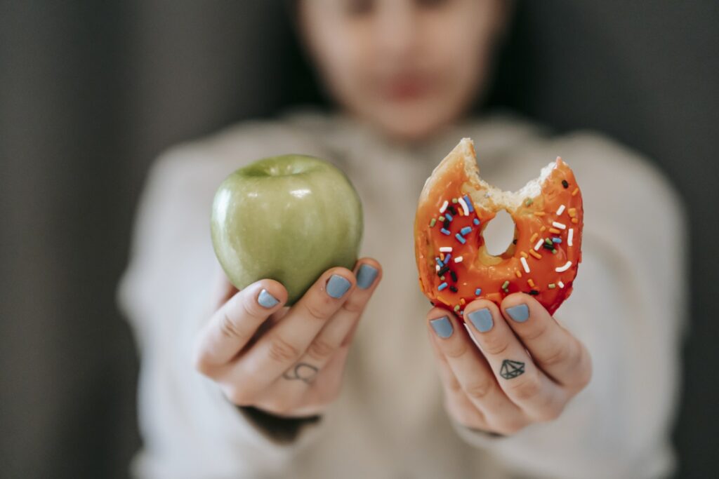 une femme montrant un donut et une pomme
